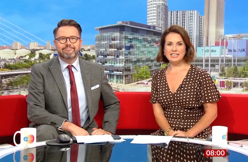 TV presenter on red sofa in polka dot dress