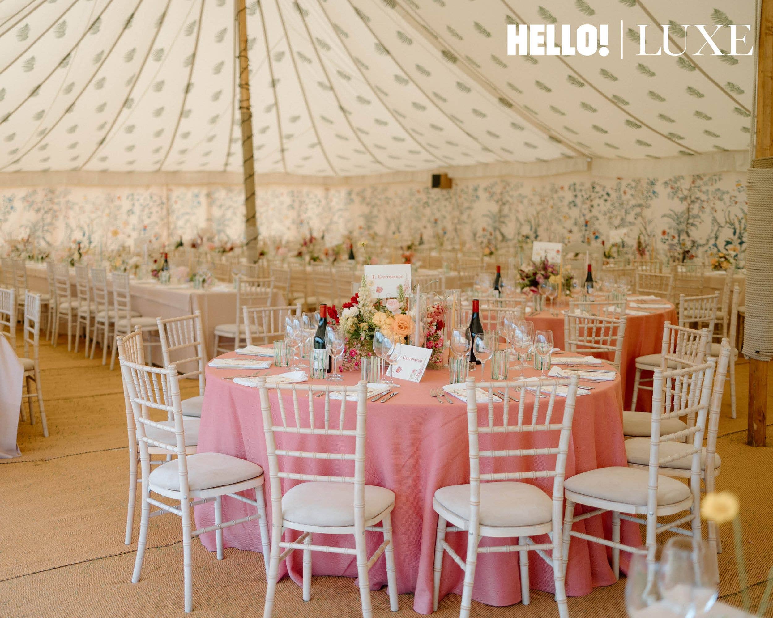 A view inside the reception marquee at Hovingham Hall, showing the tables set with pink cloths, floral centerpieces, and custom menus for the wedding breakfast