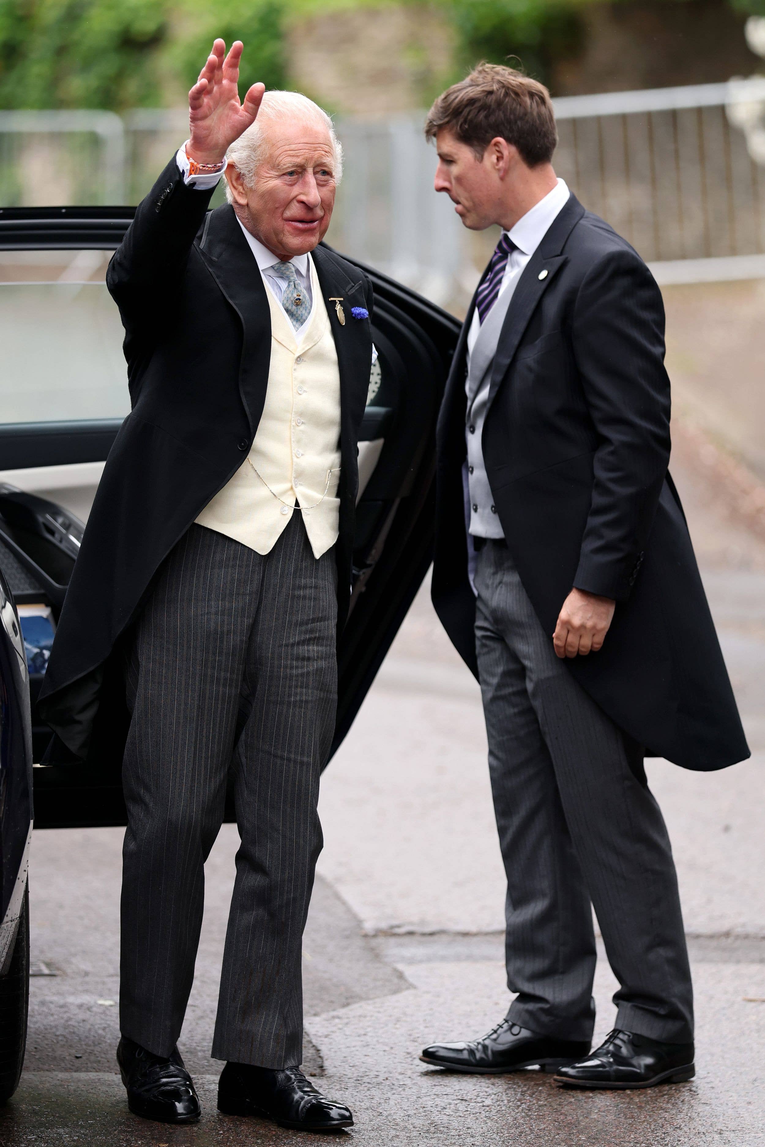 King Charles III waves as he arrives for the Royal wedding of Peter Phillips and Harriet Sperling at All Saints' Church