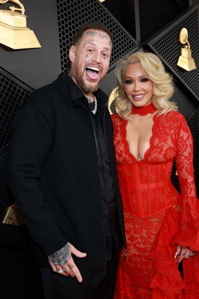 Jelly Roll and Bunnie Xo in a red dress smiling at an event.