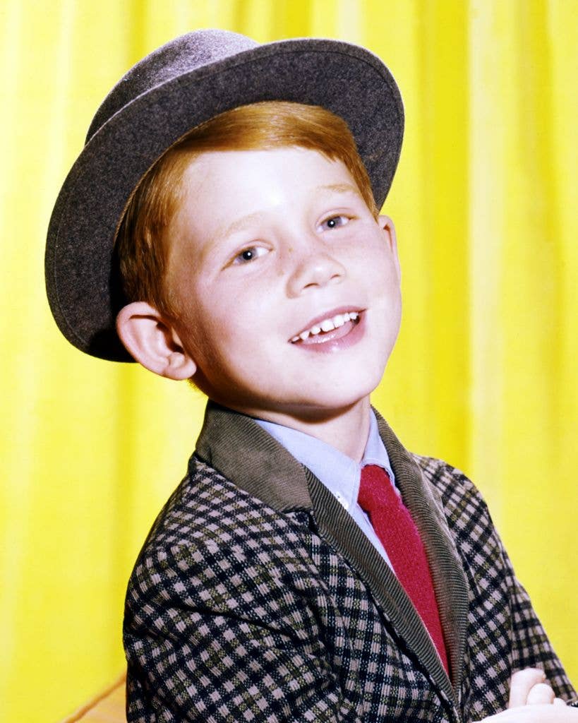 Ron Howard in a checked jacket and grey hat, against a yellow backdrop, in a studio portrait issued as publicity for the US television series, 'The Andy Griffith Show.'