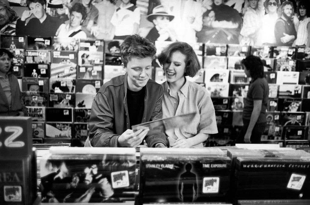 Black and white photo of Anthony Michael Hall and Molly Ringwald looking through records.