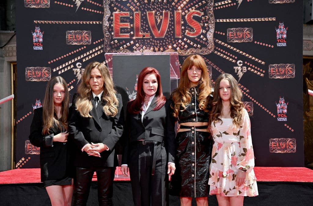 Priscilla Presley, Lisa Marie Presley, and Riley Keough stand with two other women on a red carpet.