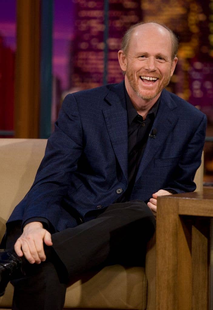 Ron Howard in a suit, with one foot crossed to his knee, laughing on The Tonight Show with Jay Leno in 2008.