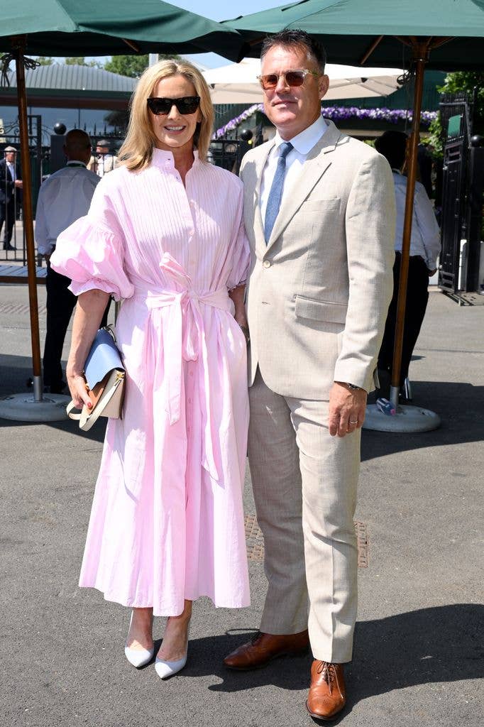 Gabby Logan in pink dress and sunglasses stands next to a man in a suit and tie.
