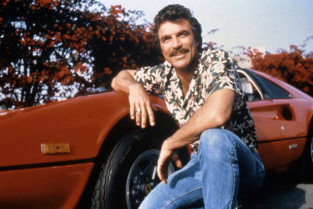 Tom Selleck posing with a red Ferrari in a still from Magnum, P.I.