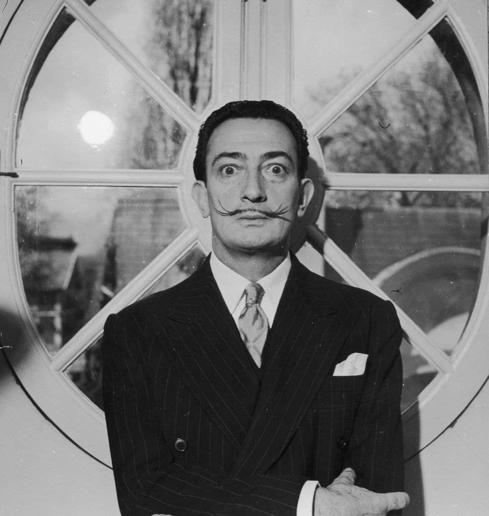 Portrait of Spanish surrealist artist Salvador Dali (1904  - 1989). He is wearing a pinstriped suit and his trademark mustache. 