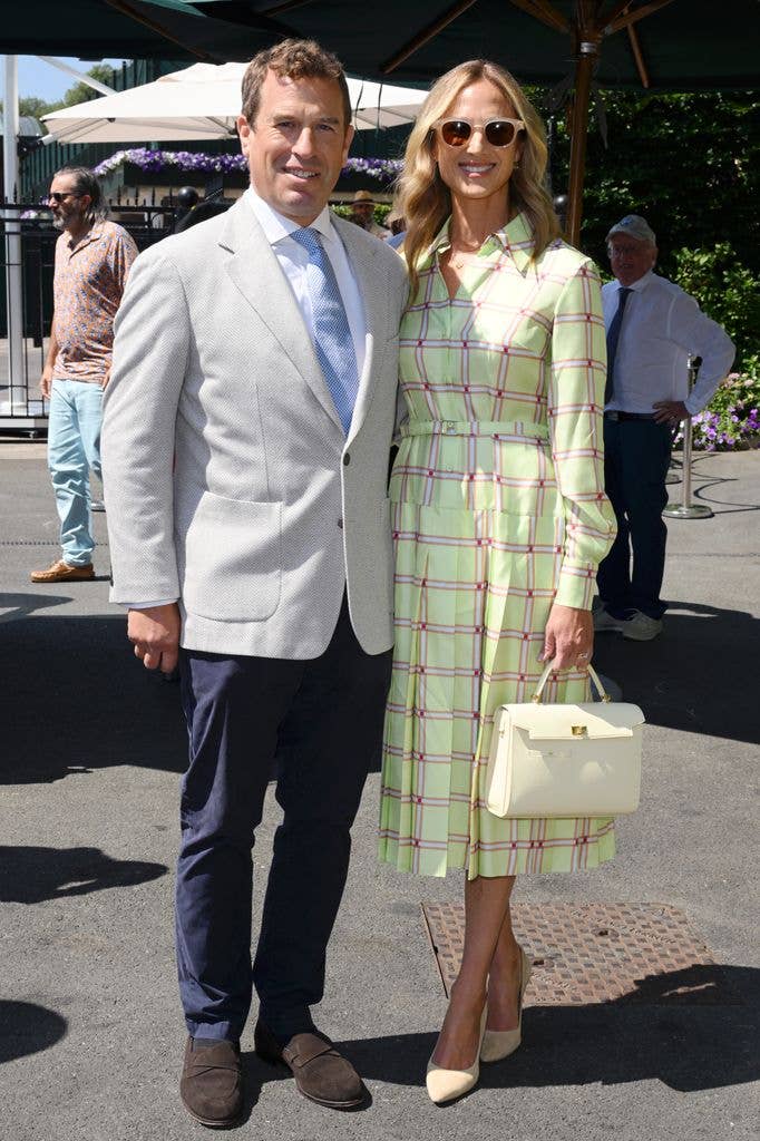 Peter Phillips and Harriet Sperling standing together, both smiling. He wears a light suit, she a green plaid dress and sunglasses.