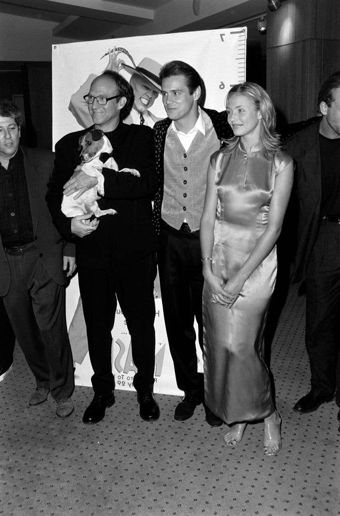 Chuck Russell holding a dog, Jim Carrey in a vest, Cameron Diaz in a dress, and other individuals at an event.