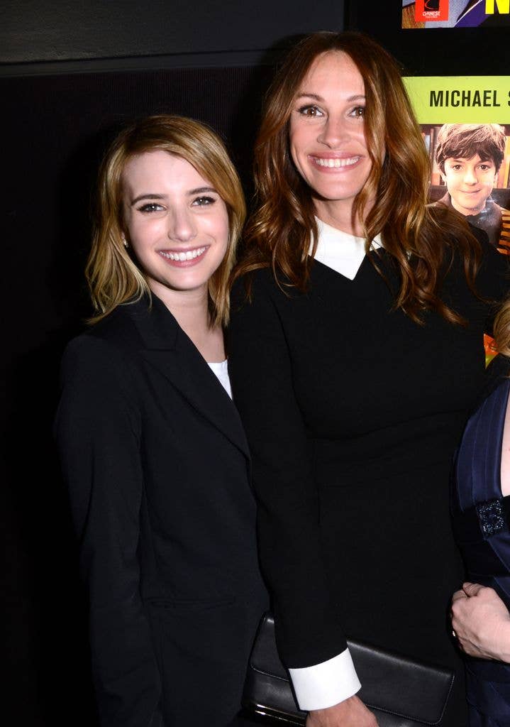 Emma smiles while wearing a black blazer next to Julia, who is also smiling and wearing a black and white collared top