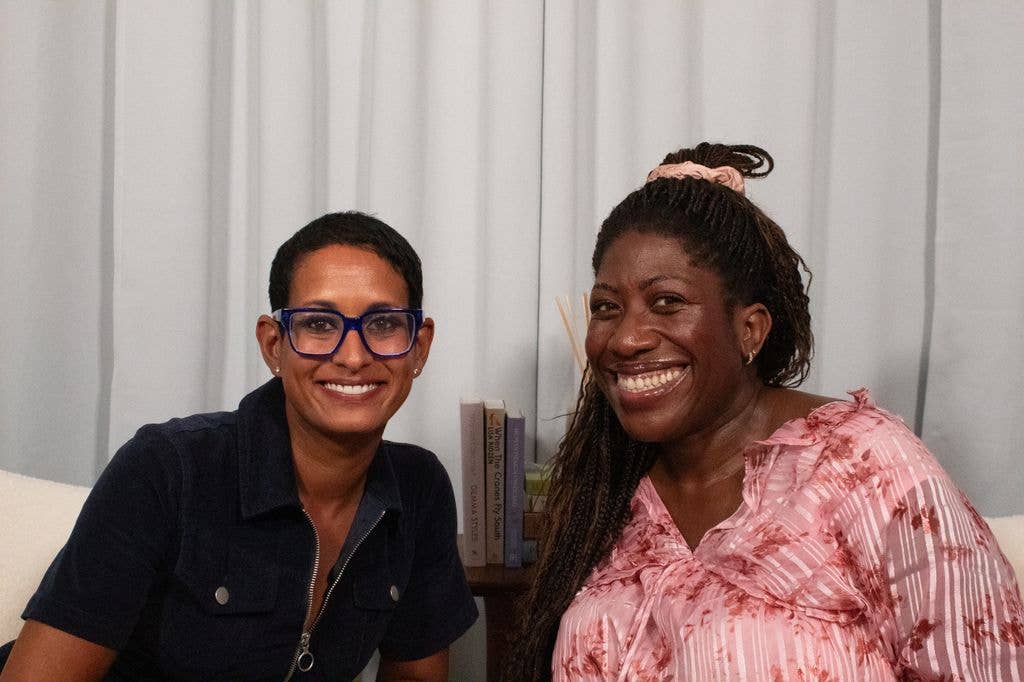 Two women smiling together in a podcast studio 
