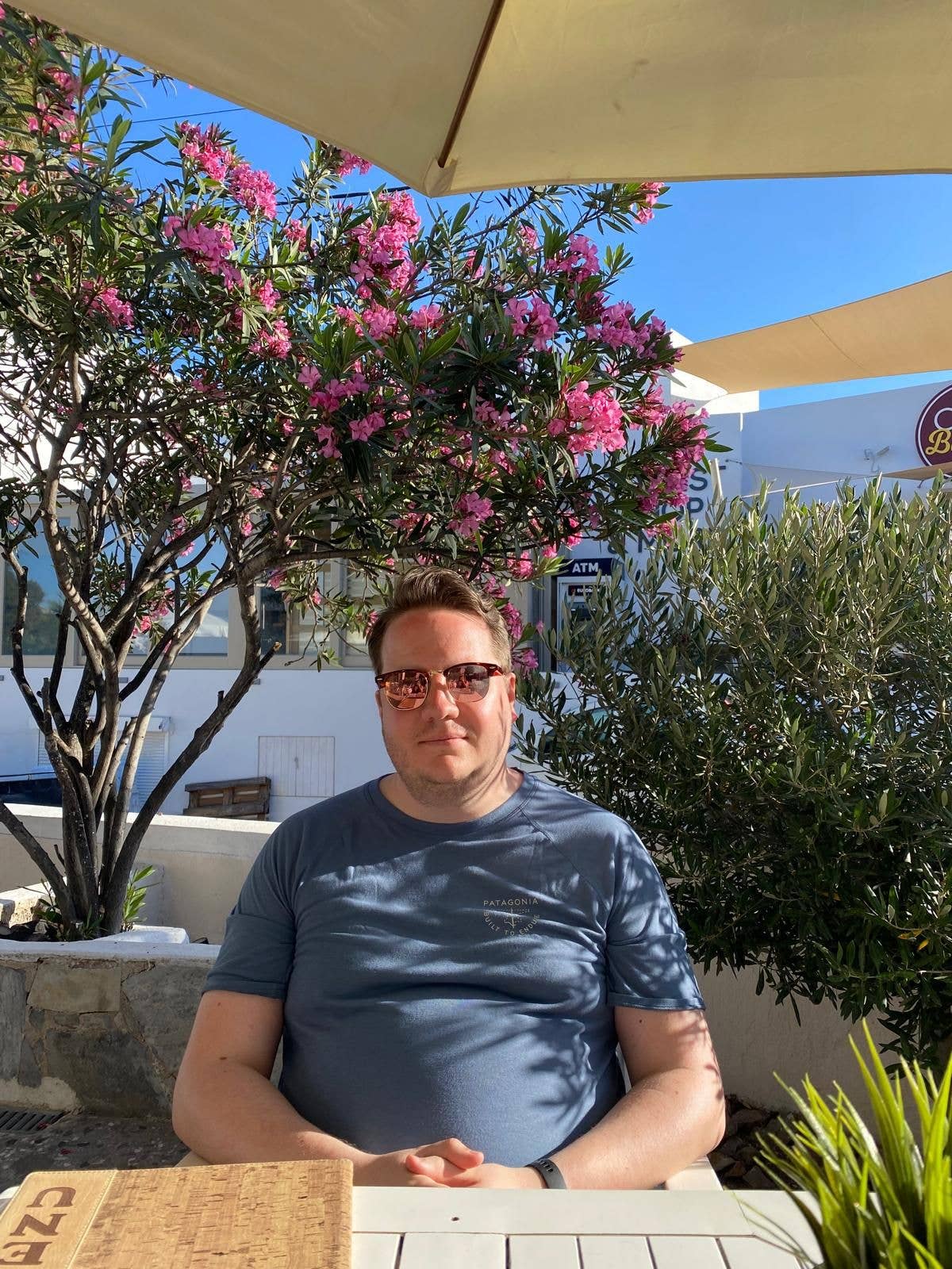 man sitting in the sun in a hot country under an umbrella 