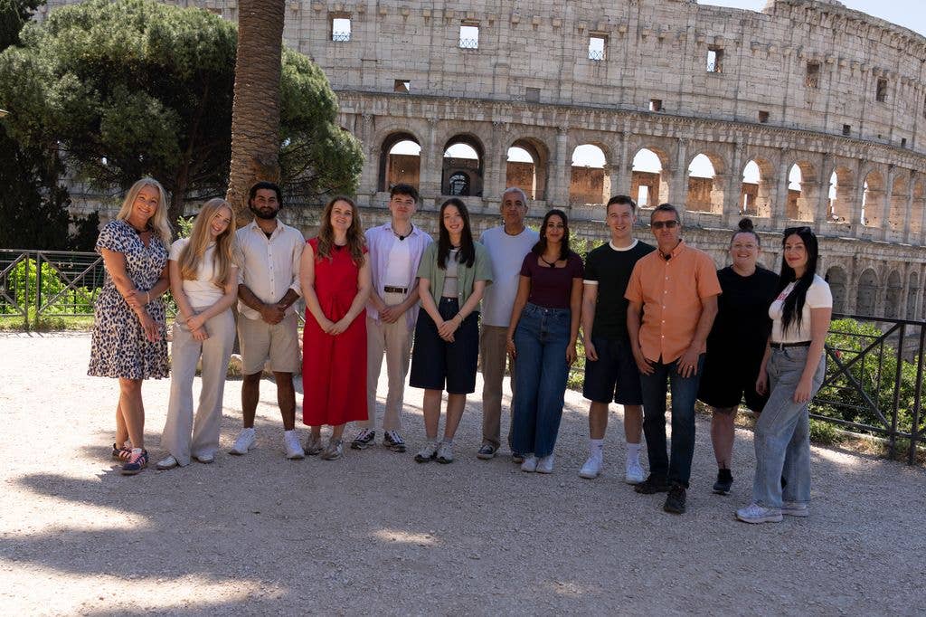 Group of people standing in front of the Colosseum, smiling for a photo.