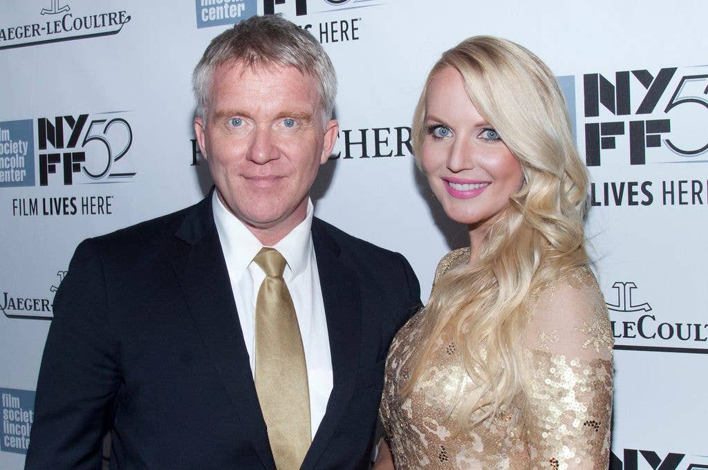 Anthony Michael Hall stands next to wife Lucia Oskerova in gold tie matched to her dress. 