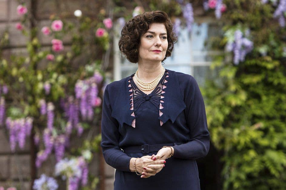 Woman in navy dress standing outside of house