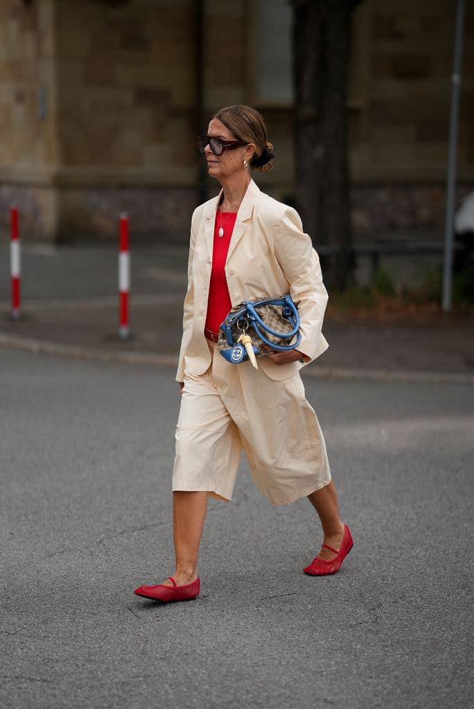Yvonne Schuppler-Kammerer is seen wearing a cream double breasted blazer from Zara; a red sleeveless top from Zara; a cream Bermuda shorts from Zara with a brown leather belt from Mango; red mesh Mary Jane ballet flats; a vintage beige and brown Monogram canvas handbag with blue leather handles and gold tone hardware from Gucci; a pendant necklace from Dremiskin and a red bracelet from H&M; oversized tortoiseshell frame sunglasses with dark tinted lenses from Gina Tricot; brown hair worn in a sleek low bun on August 7, 2026 in Frankfurt am Main, Germany. (Photo by Moritz Scholz/Getty Images)