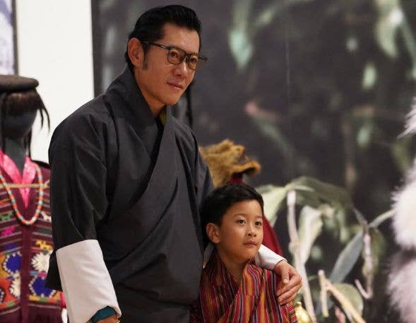 Jigme Khesar Namgyel Wangchuck in traditional attire with a young boy in striped robe.