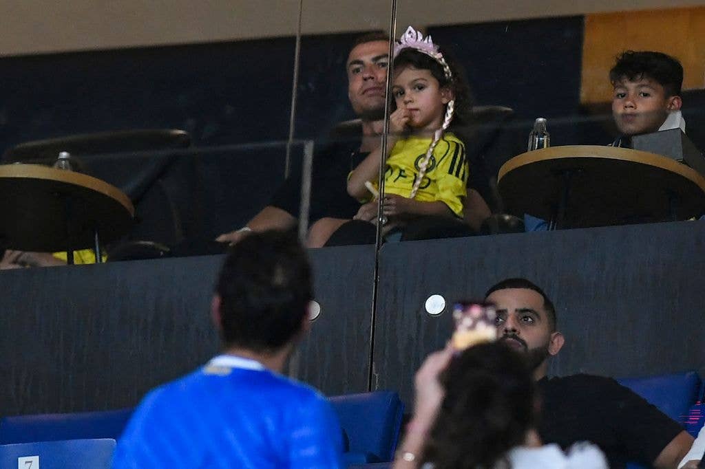 Cristiano held one of his daughters on his knee as they watched the match