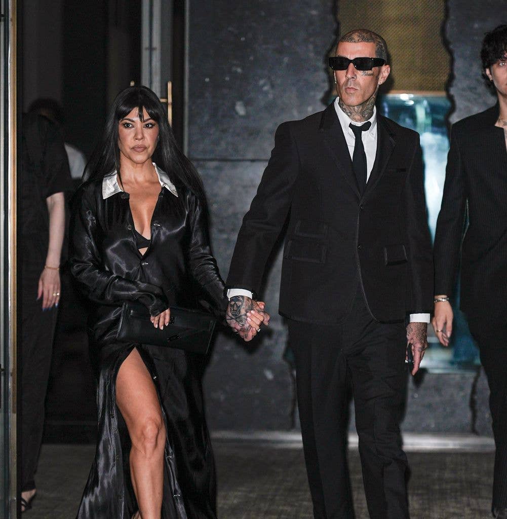 Kourtney Kardashian and Travis Barker walking hand in hand in matching black outfits 