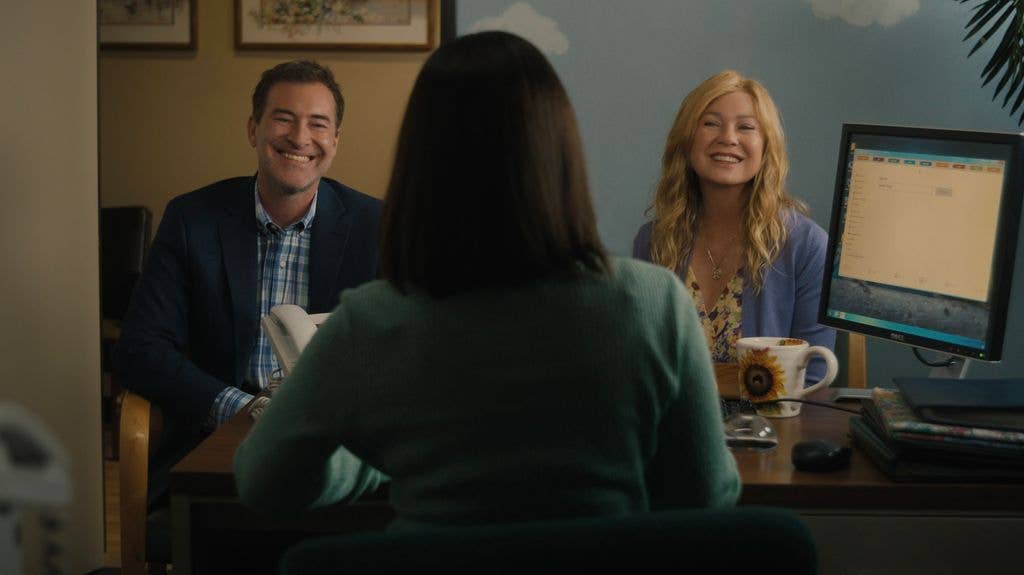 Man and women smiling at woman sitting in office