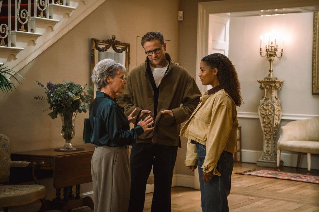 Josh Dylan stands between two women, one with short gray hair, in a hallway.