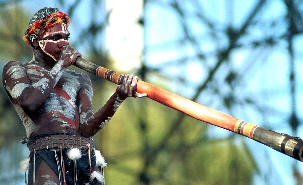 Yothu Yindi perform on stage, with a member playing didgeridoo, at the F1 Grand Prix in March 1997 in Melbourne, Australia.