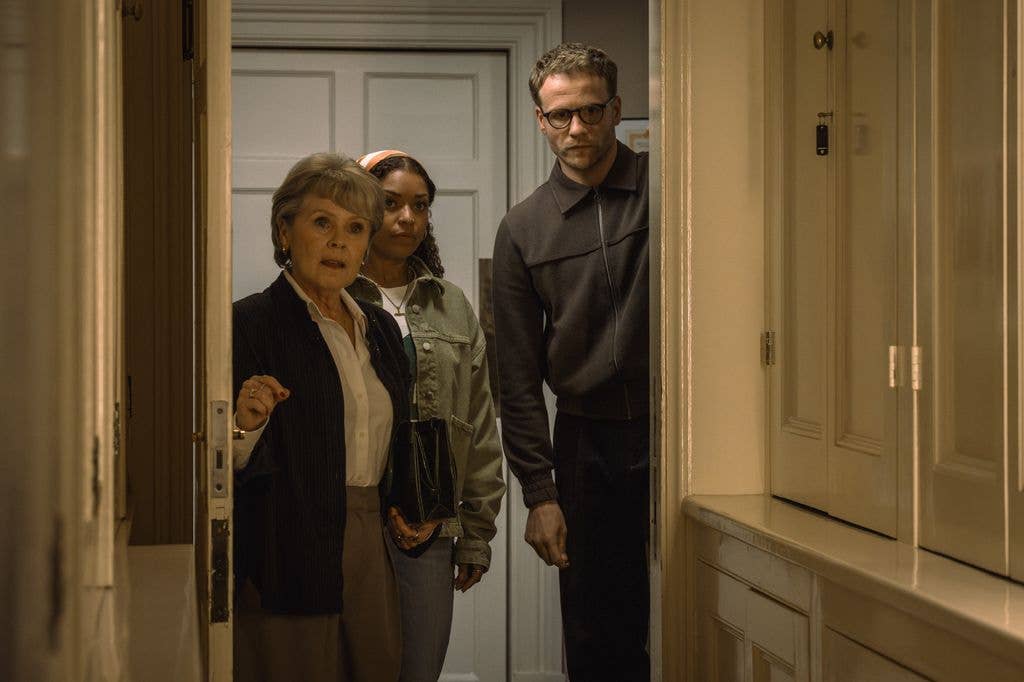 Josh Dylan stands in doorway with two women, one holding a purse.