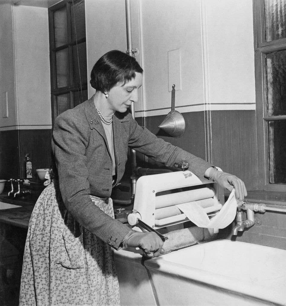 Scottish governess Marion Crawford (1909 - 1988), an employee of the British royal family, uses a hand-cranked mangle in the kitchen