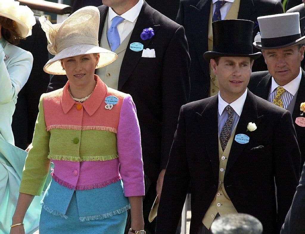 Sophie, Duchess of Edinburgh in colorful outfit and hat, walking with Prince Edward in formal wear.