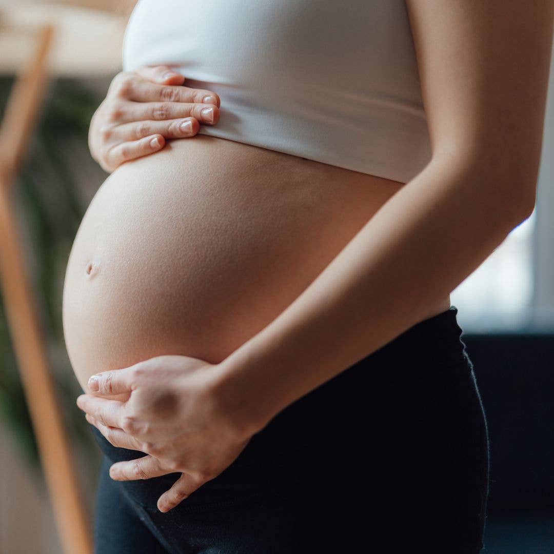Side view close-up of pregnant woman touching her belly. Pregnancy health & wellbeing concept.