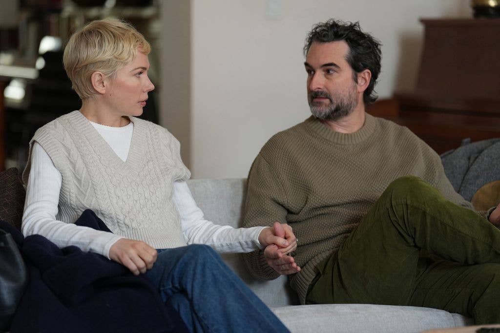 Man and woman holding hands sitting on grey sofa