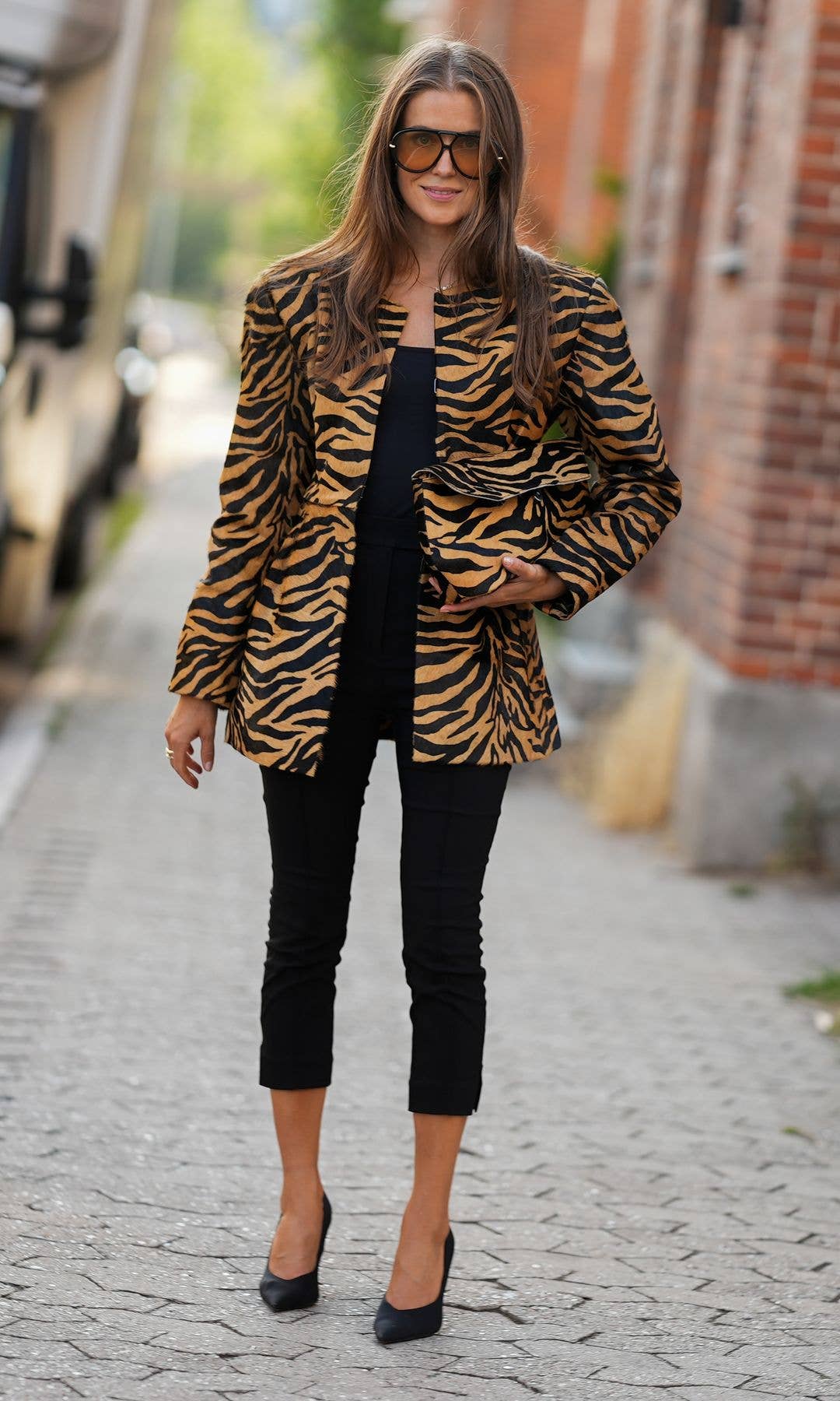 Nina Sandbech is seen wearing a tiger print blazer, a black top, black cropped trousers, oversized sunglasses, black pointed toe pumps and carrying a matching tiger print clutch outside the Gestuz show during Day 2 of Copenhagen Fashion Week Spring Summer 2027 on August 4, 2026 in Copenhagen, Denmark. (Photo by Moritz Scholz/Getty Images)