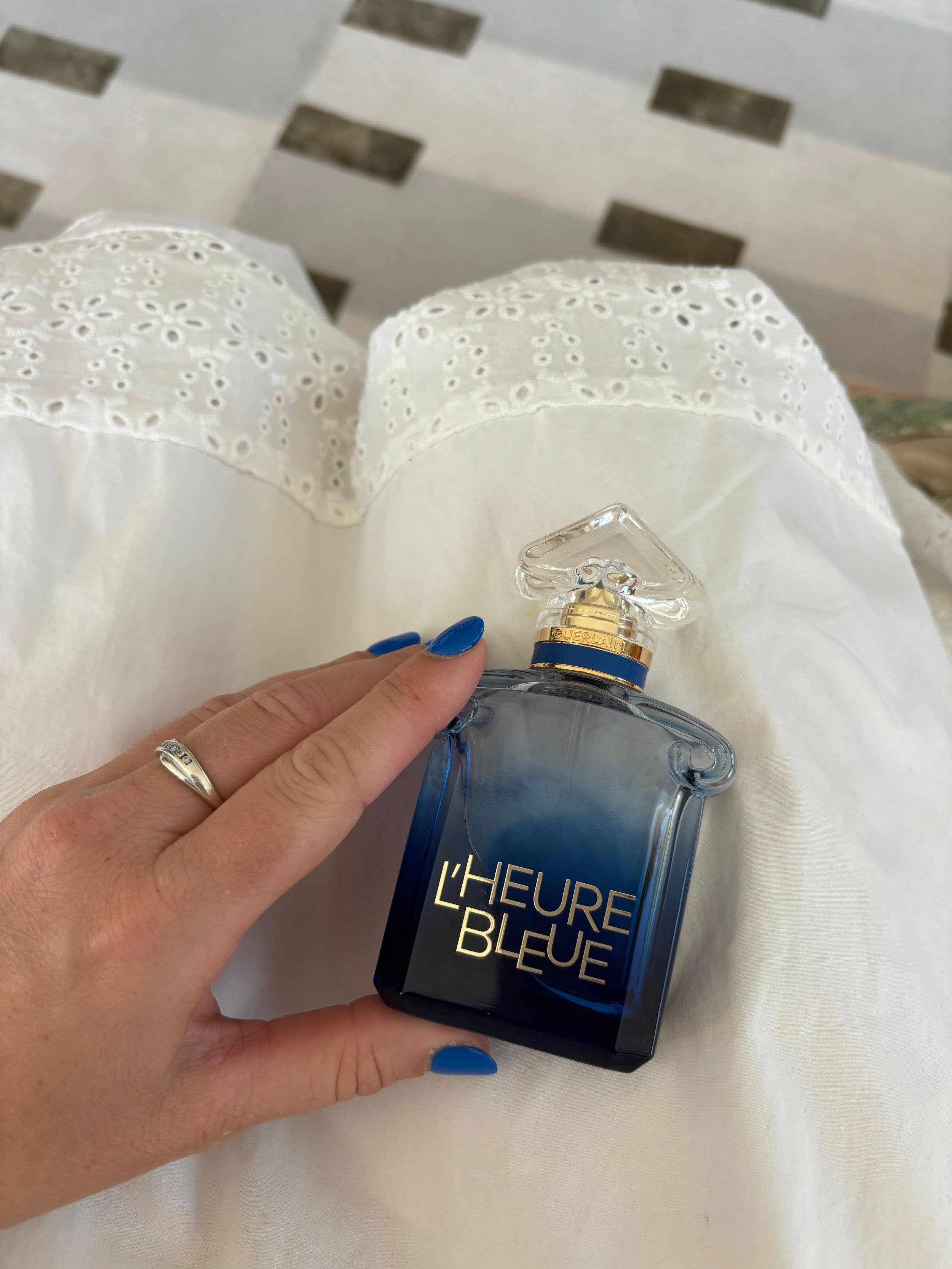 L'Heure Bleue perfume bottle in front of a white skirt