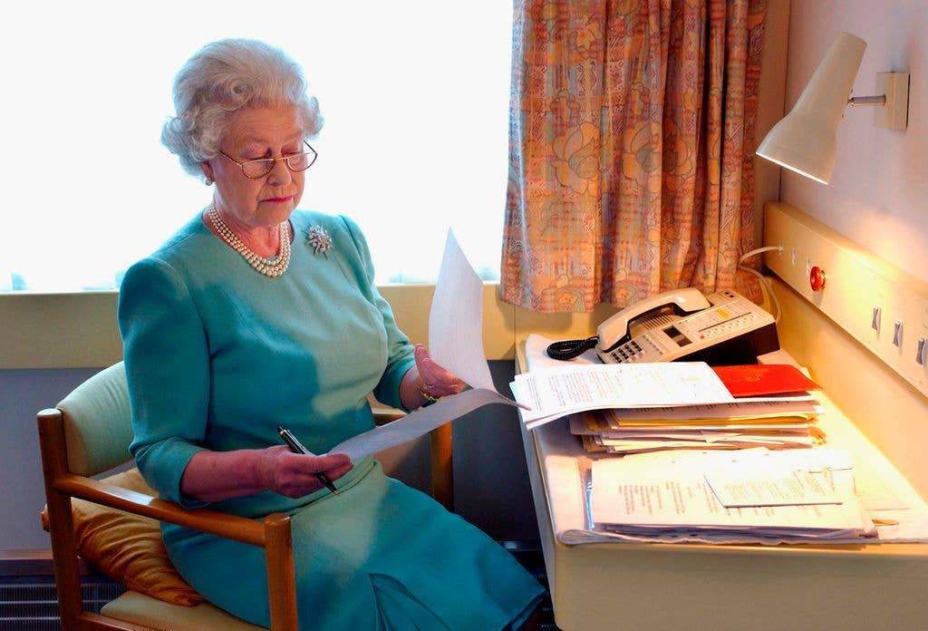 Queen Elizabeth II looking at papers at her desk on the royal train