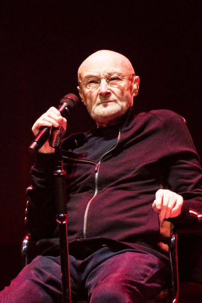 Phil Collins sitting down at a performance in Berlin