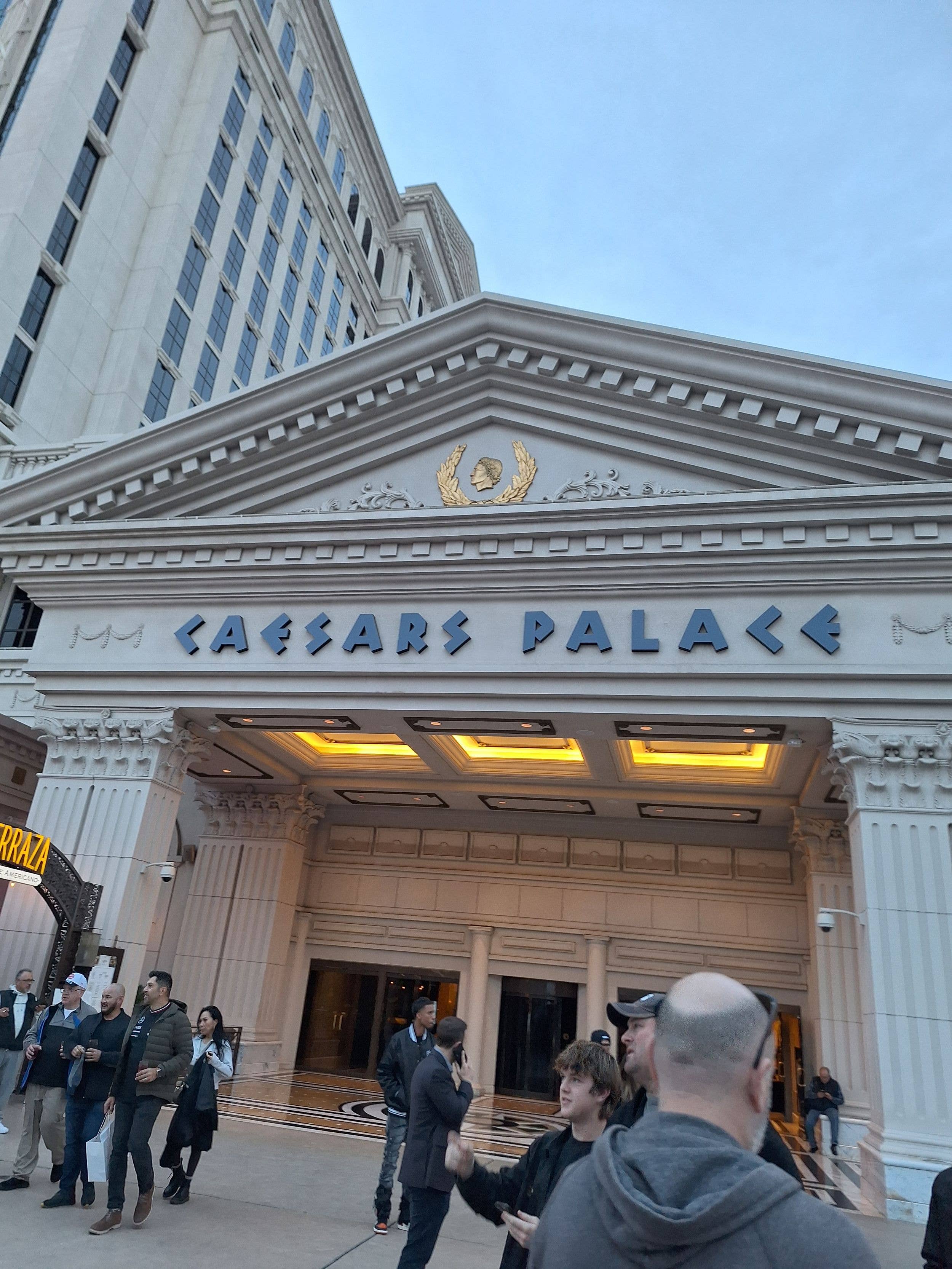 Group of people outside a large building with 'CAESARS PALACE' written on it.