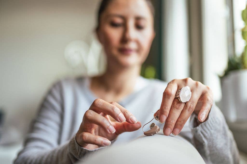 Young Adult Woman inserting battery into the Hearing Aid