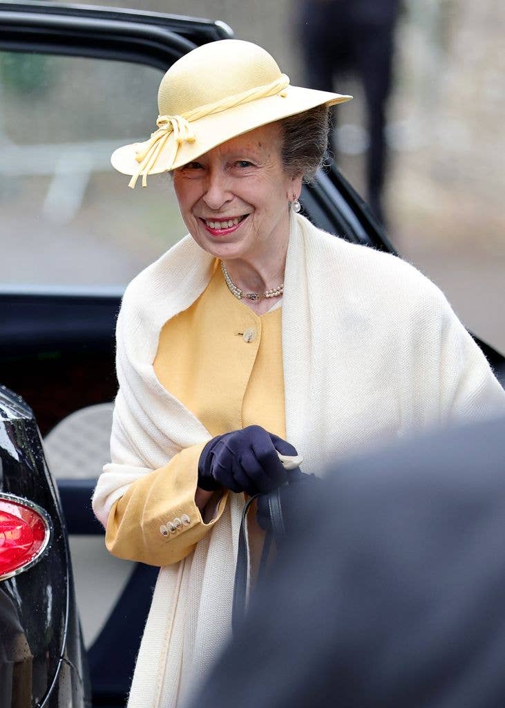Princess Anne smiling wearing a yellow fascinator hat 