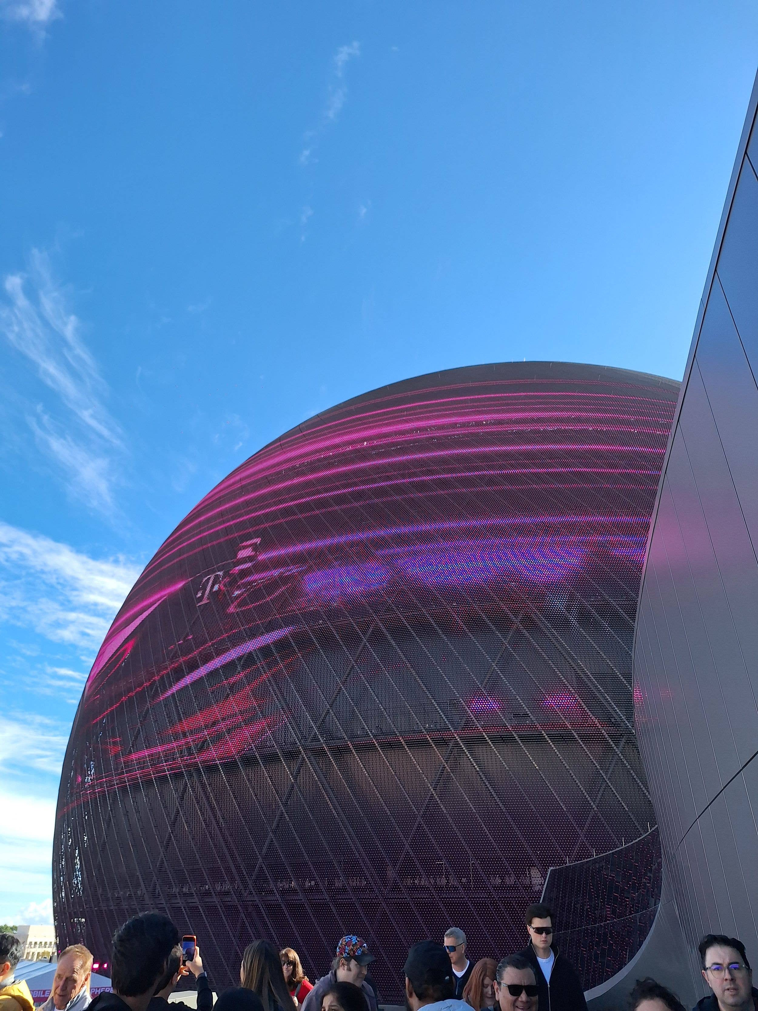 Group of people, some wearing sunglasses, standing under a large, colorful dome structure.
