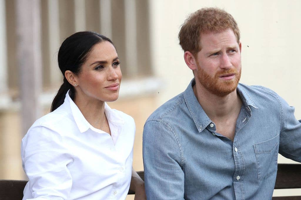 Prince Harry and Meghan Markle wearing shirts and gazing into the distance