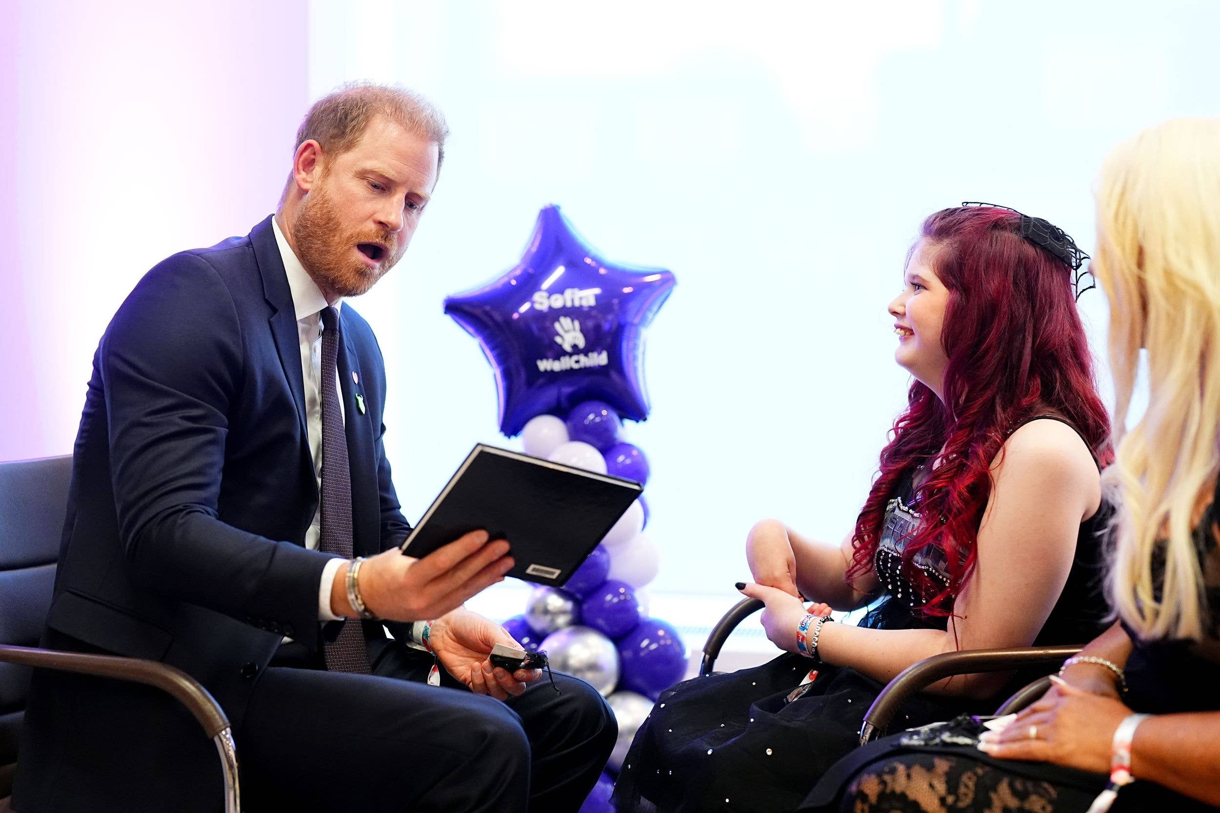 Prince Harry, Duke of Sussex is shown a book of when the winner of the Inspirational Young Person 12-14, Sofia Dobson (C) met band Metallica, during the WellChild Awards 2026, during the 2026 Wellchild Awards at the Royal Lancaster Hotel on September 21, 2026 in London, England.