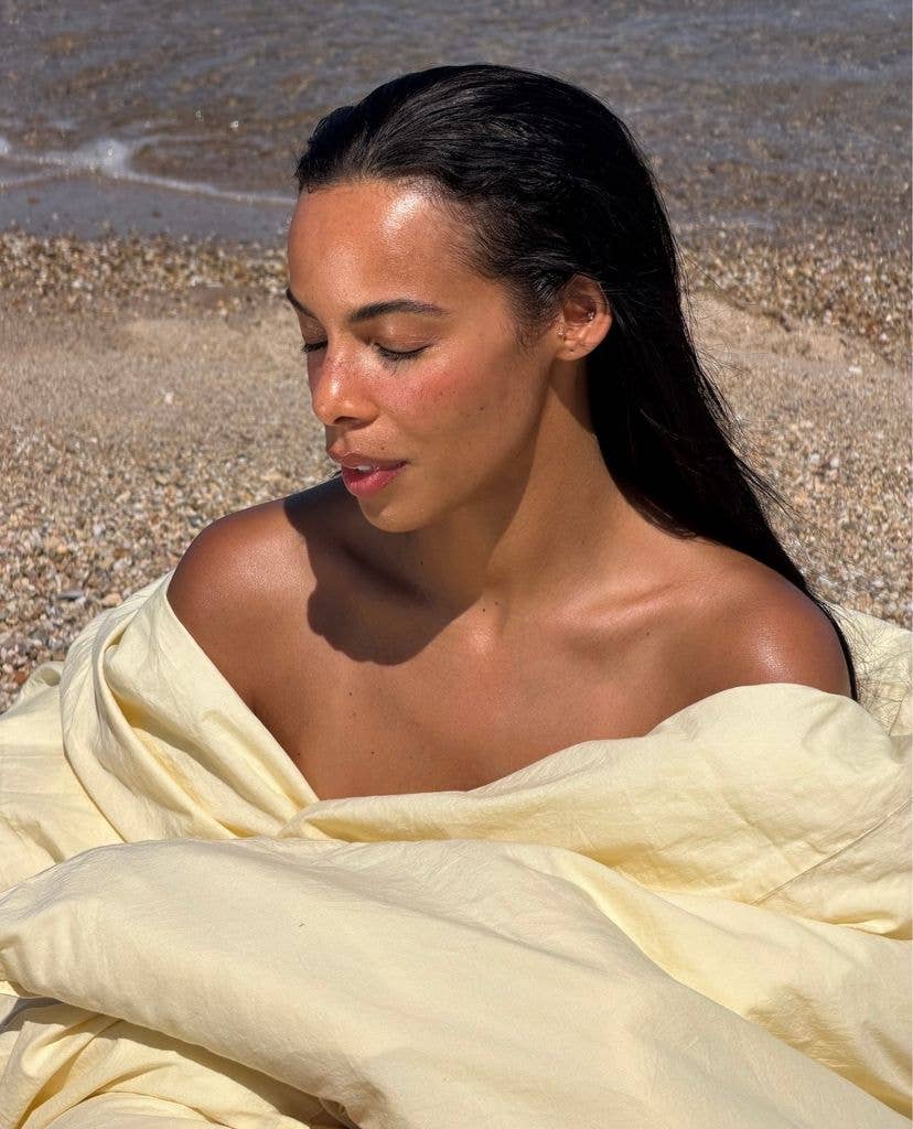 Rochelle' Humes sitting on the beach wrapped in a blanket