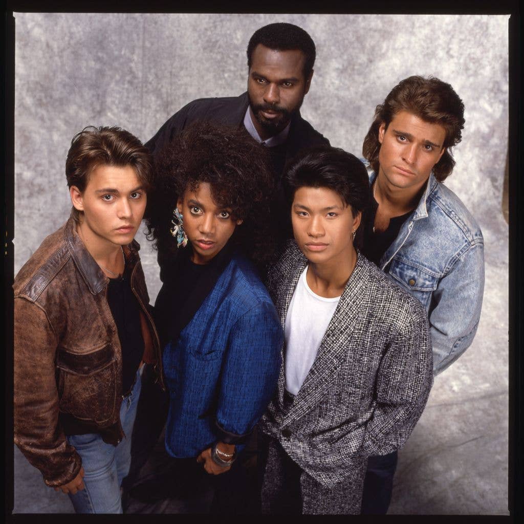 Johnny Depp, Holly Robinson Peete, Steven Williams, Dustin Nguyen and Peter DeLuise pose together in a group portrait against a mottled grey backdrop.