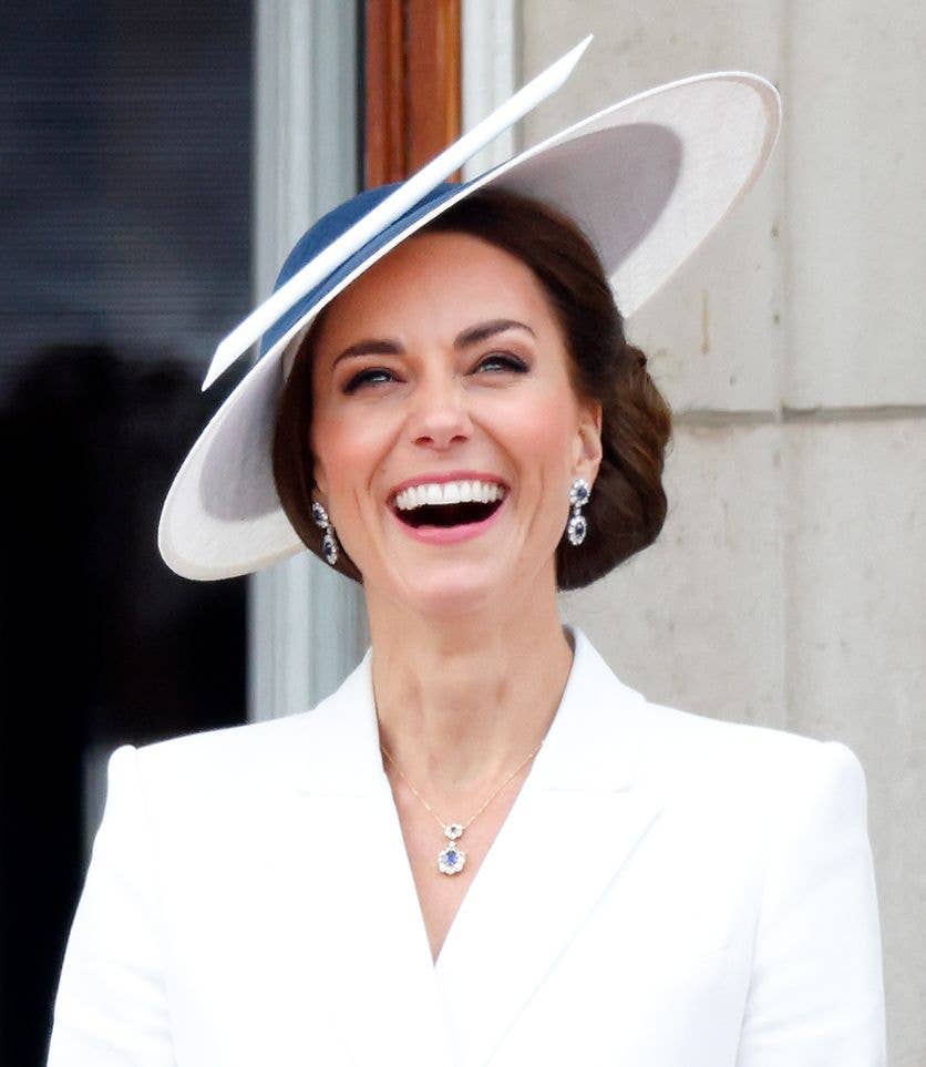 Kate Middleton wearing a white blazer and a navy blue hat, watches a flypast from the balcony of Buckingham Palace during Trooping the Colour on June 2, 2022 in London, England. 