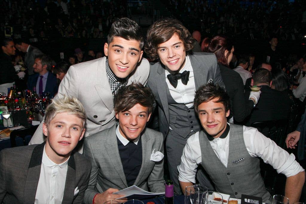 Niall Horan, Zayn, Louis Tomlinson, Harry Styles and Liam Payne of One Direction smile for the camera seated at a table during The BRIT Awards 2012.