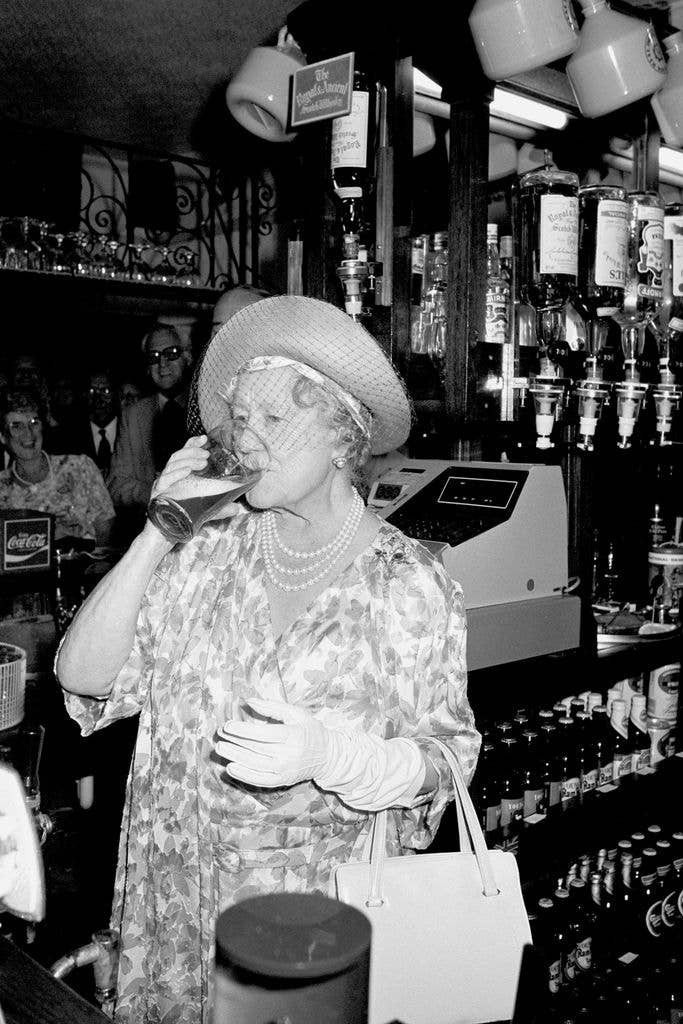 The Queen Mother enjoys a pint of bitter which she pulled herself, during a visit to The Queens Head pub in Stepney in London's East End.