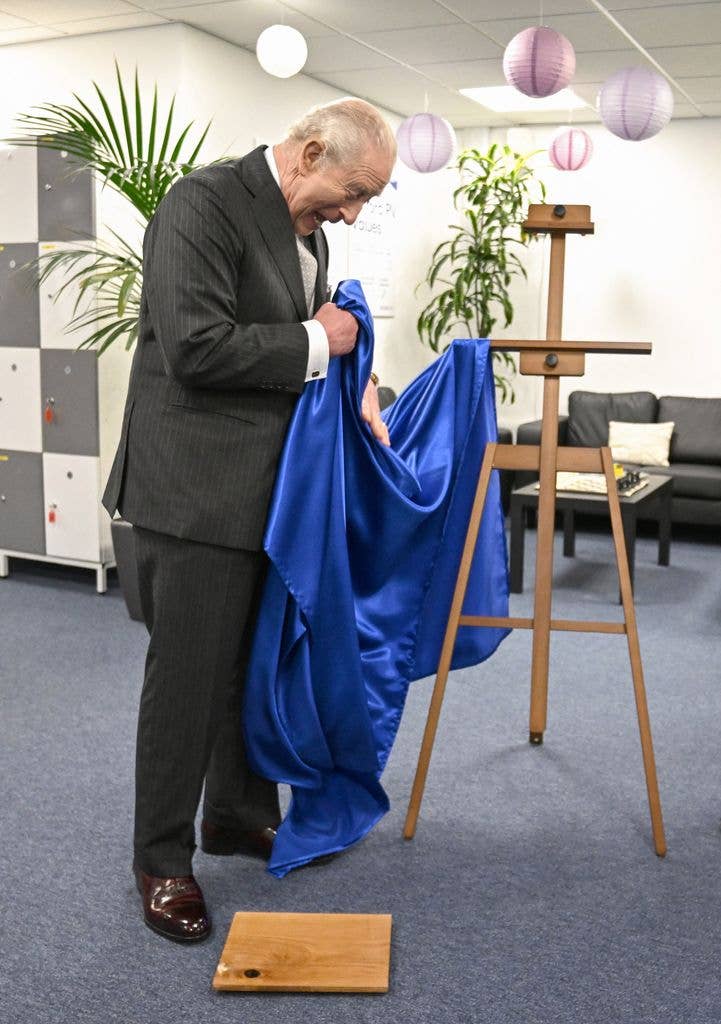 Britain's King Charles III reacts as he unveils a plaque which accidentally falls to the floor during a visit to Oxford Photovoltaics an enterprise developing advanced solar panels, in Kidlington, Oxfordshire, west of London on March 27, 2026