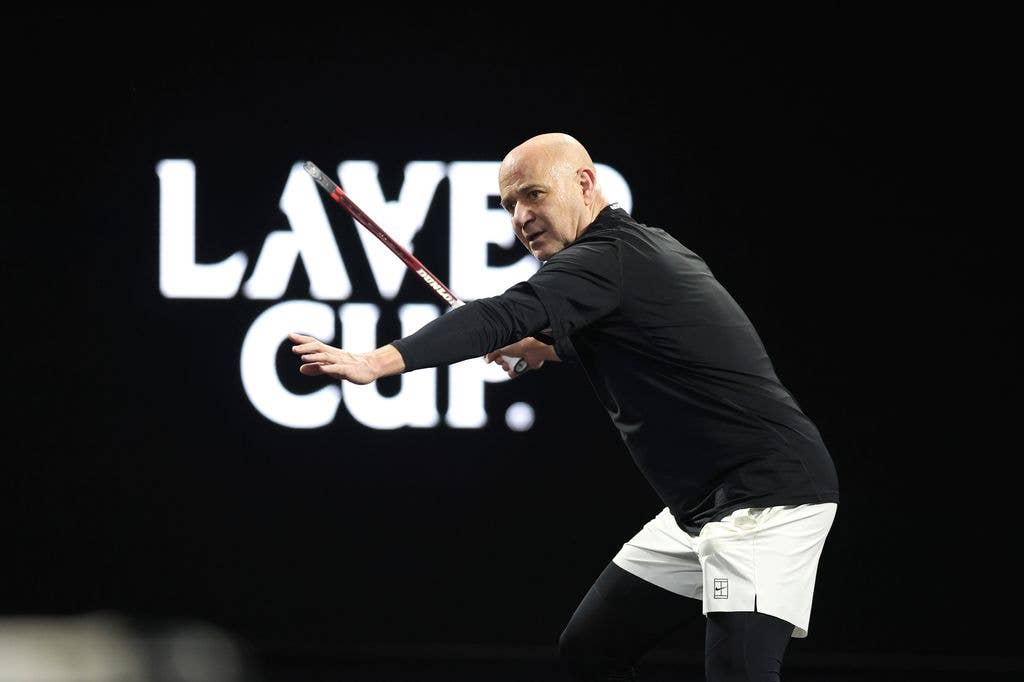 Andre Agassi playing tennis, holding a racket, wearing black and white athletic gear.