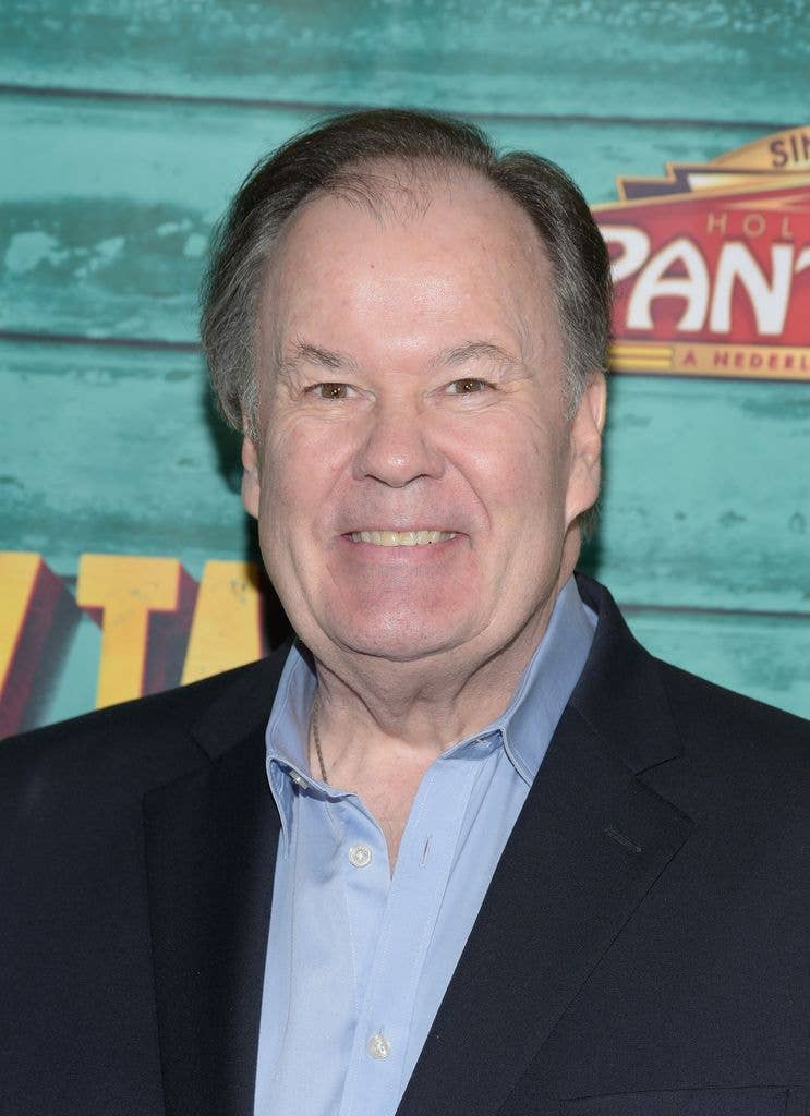 Dennis Haskins smiling in a black suit and blue shirt at an event.