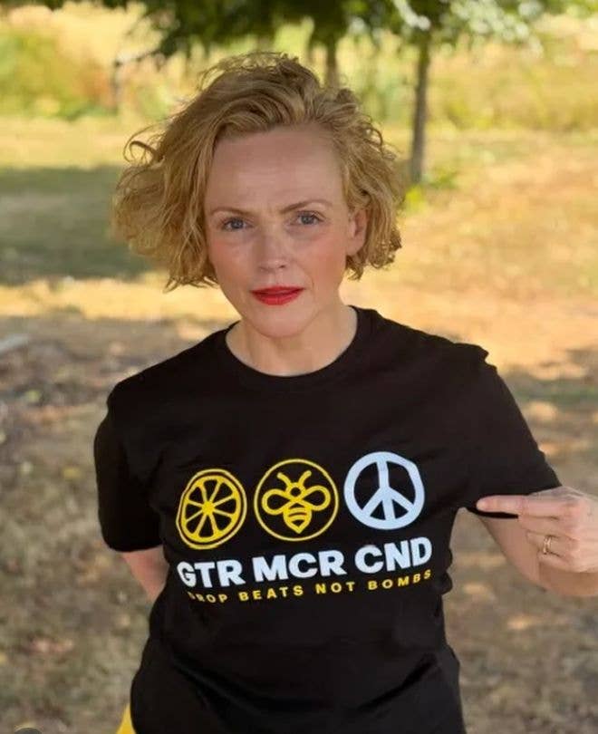 Maxine Peake stands in a park wearing a black t-shirt with peace and bee symbols.